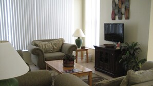 A living room with a sofa, a coffee table, a lamp, a television, and a cabinet. - Ov2287 - Espirit - 3 Bed 2 Baths Villa (Davenport)