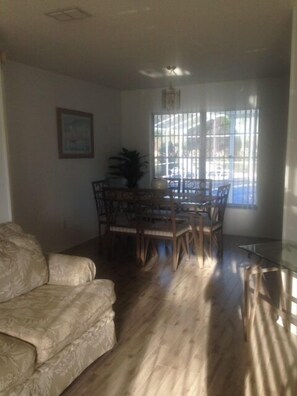 A living room with a sofa, a dining table with chairs, a potted plant, and a window with bars. - Ovm2258 - Indian Ridge - 4 Bed 2 Baths Villa (Kissimmee)