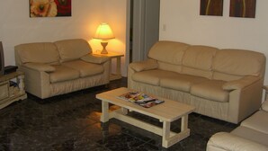 Sala de estar com dois sofás bege, uma mesinha de centro de madeira e uma luminária.