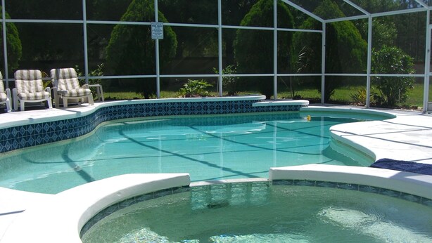 Piscina com borda azulejada e uma banheira de hidromassagem.
