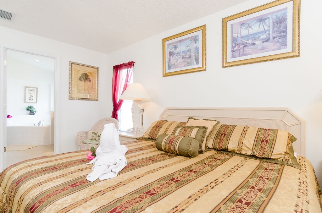 A bedroom with a bed, a nightstand, a chair, and two framed pictures on the wall.