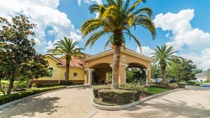 A building with a covered entrance, palm trees, and a paved walkway. - Ovm1754 - Terra Verde Resort - 4 Bed 3 Baths Townhome (Kissimmee)