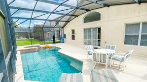 A swimming pool with a glass enclosure, surrounded by outdoor furniture and a covered patio area. - Ovm1754 - Terra Verde Resort - 4 Bed 3 Baths Townhome (Kissimmee)