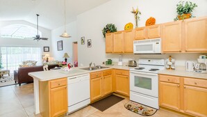 A modern kitchen with wooden cabinets, white appliances, and a large island. - Ovm1754 - Terra Verde Resort - 4 Bed 3 Baths Townhome (Kissimmee)