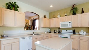 A modern kitchen with light wooden cabinets, a central island, a microwave, and a dishwasher. - Ov1138 - Emerald Island - 7 Bed 4.5 Baths Villa (Kissimmee)