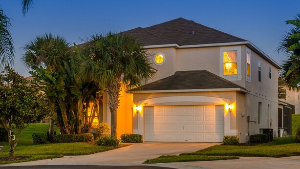 A two-story house with a garage, surrounded by palm trees and well-maintained lawns. - Ov1138 - Emerald Island - 7 Bed 4.5 Baths Villa (Kissimmee)