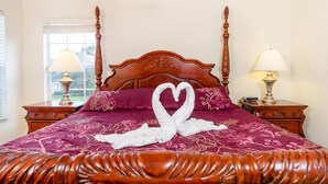 Een hemelbed met een handdoek in de vorm van een hart, een raam met uitzicht en twee bedlampjes.