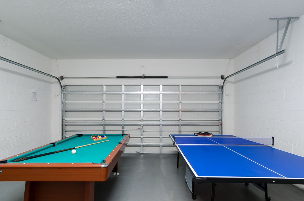 Ein Zimmer mit Billardtisch, Tischtennisplatte und Garagentor.