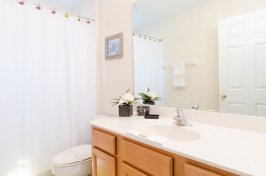 A bathroom with a white sink, wooden cabinets, a mirror, and a shower curtain.