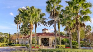 A building with a red-tiled roof, a central entrance, and palm trees in the foreground. - Ov474 - Emerald Island - 7 Bed 6 Baths Villa (Kissimmee)