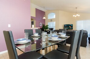 A dining area with a glass table set for six, surrounded by black chairs. - Ov1030 - Emerald Island - 4 Bed 3 Baths Townhome (Kissimmee)