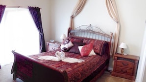 A bedroom with a four-poster bed, a nightstand, a lamp, and a window with curtains. - Ov2672 - Lindfields - 4 Bed 3 Baths Villa (Kissimmee)