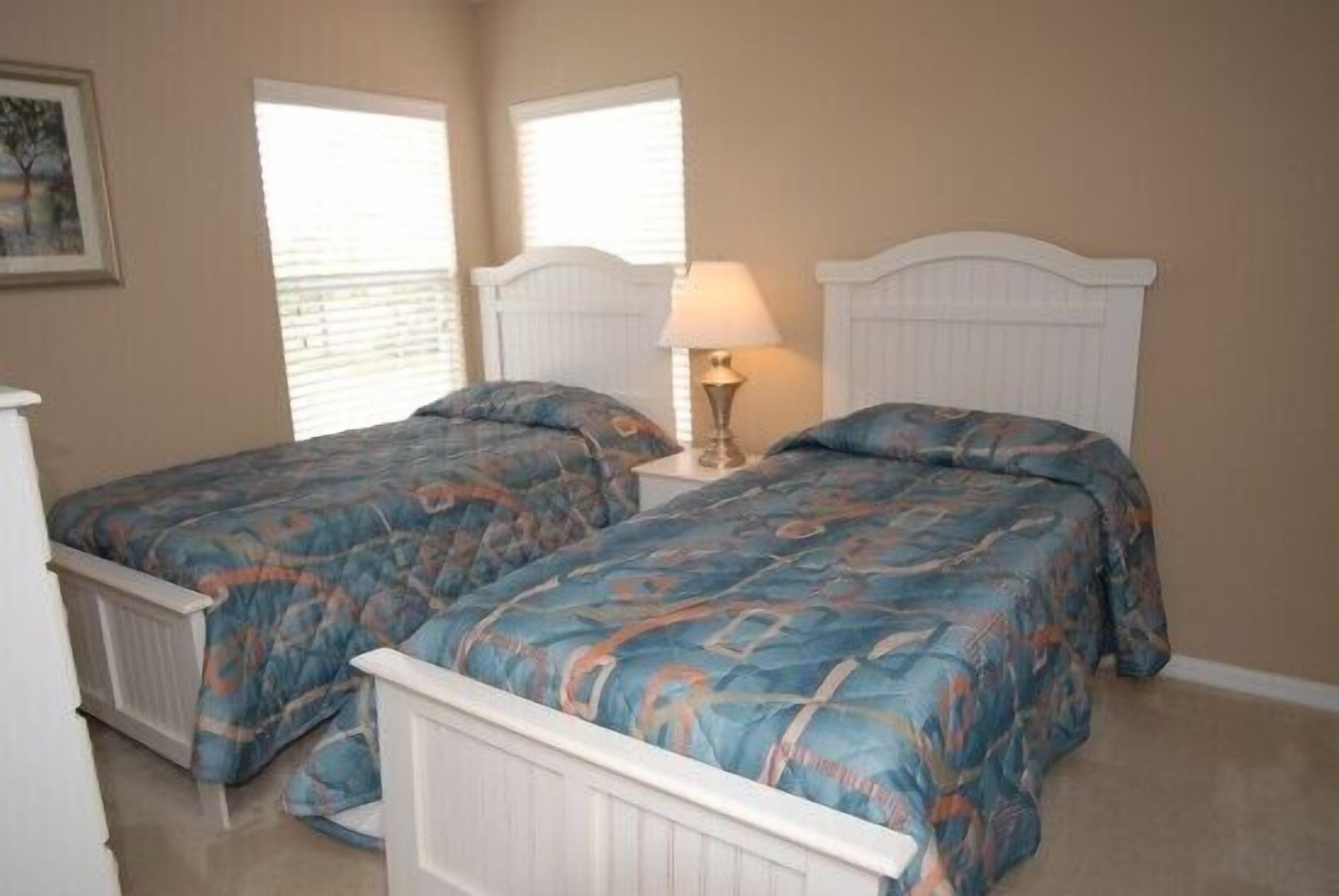 A bedroom with two single beds, a nightstand with a lamp, and a radiator.