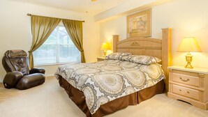 Ein Schlafzimmer mit einem Bett, zwei Nachttischlampen, einem Kopfteil, einem Sessel und einem Deckenventilator.