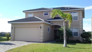 A two-story house with a garage, a covered patio, and a well-maintained lawn. - Ov4069 - Vista Park - 5 Bed 4 Baths Villa (Davenport)