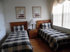 A room with two beds, each with a checkered bedspread, a nightstand with a lamp, and two framed pictures of sailboats on the wall. - Ov4069 - Vista Park - 5 Bed 4 Baths Villa (Davenport)
