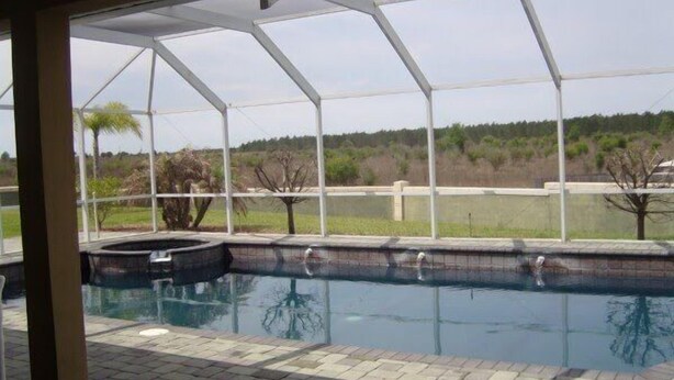 A covered outdoor swimming pool with a view of a landscaped area and trees. - Ov4069 - Vista Park - 5 Bed 4 Baths Villa (Davenport)
