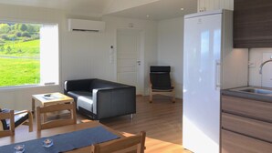 Een ruimtelijk ingerichte leefruimte met kitchenette, eethoek en zithoek met een bank en stoelen.