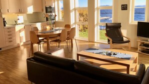 Een moderne keuken met houten kastjes, een eethoek met tafel en stoelen, een leren bank en een televisie.