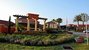A landscaped area with a pergola structure, palm trees, and a flagpole. - Ov3875 - Solana - 6 Bed 5 Baths Townhome (Davenport)