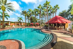 A swimming pool surrounded by palm trees and lounge chairs.