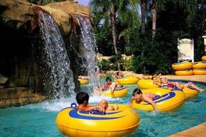Ein Wasserpark mit Personen auf gelben Wasserschläuchen und einem Wasserfall.