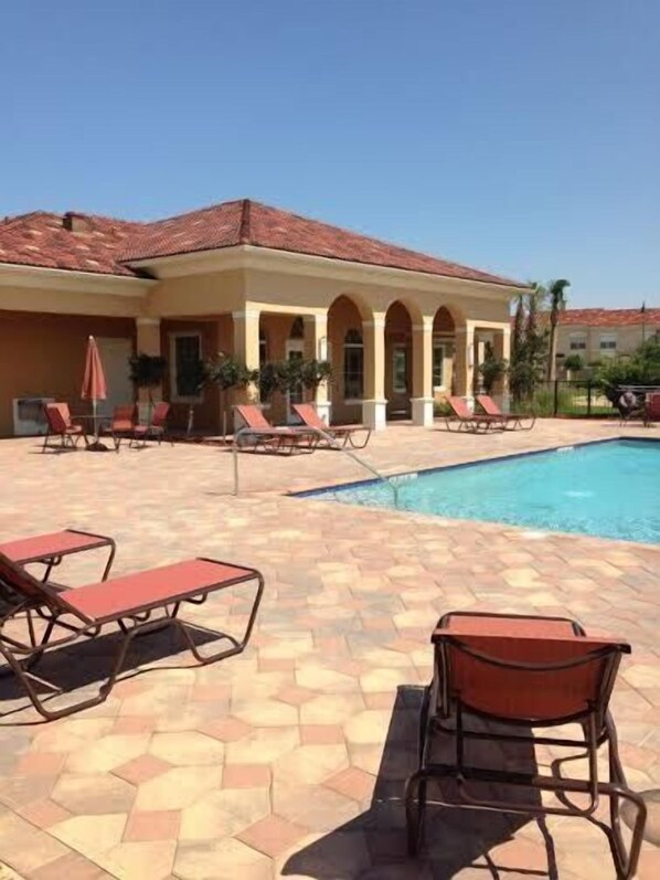 A poolside area with lounge chairs and a building with a tiled roof.