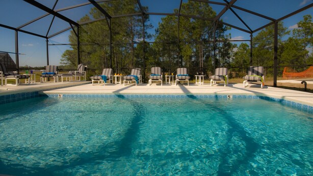 A pool area with a covered seating area and lounge chairs.