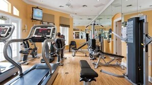 Un gimnasio con cintas de correr, una banca y máquinas de pesas.