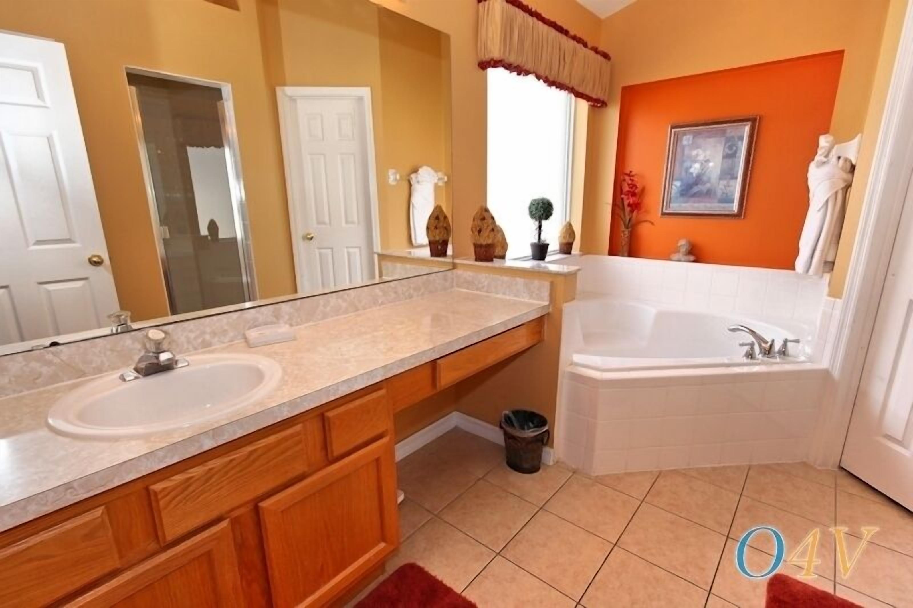 Un baño con tocador de doble lavabo, bañera y un espejo grande.