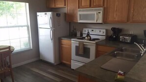 Une cuisine avec des meubles de rangement en bois, un réfrigérateur, un four à micro-ondes, une cuisinière et un évier.