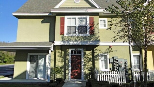 A two-story house with a front porch, a garage, and a picket fence.