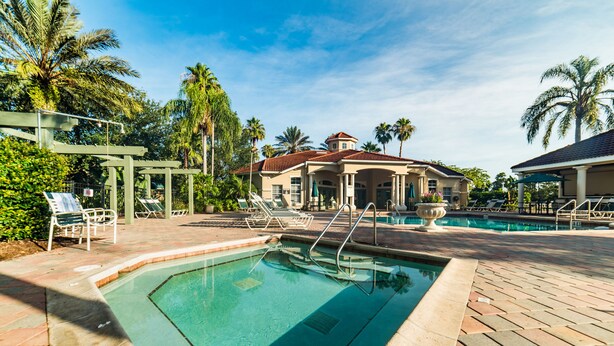 A swimming pool area with lounge chairs, a palm tree, and a building with a red roof. - Ov3990 - Emerald Island - 7 Bed 4.5 Baths Villa (Kissimmee)