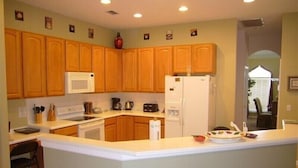 A kitchen with wooden cabinets, a white refrigerator, and a microwave. - Ov4075 - Highlands Reserve - 4 Bed 3 Baths Villa (Davenport)