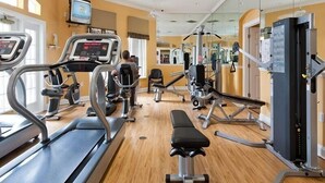 Un gimnasio con cintas de correr, bancos y máquinas de pesas.