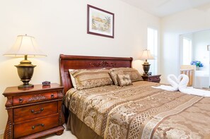 A neatly arranged hotel room with a large bed, two bedside tables with lamps, a dresser, and a framed picture on the wall. - Ovm648 - Emerald Island - 7 Bed 4 Baths Villa (Kissimmee)