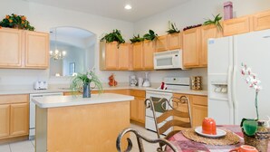 Une cuisine moderne avec des meubles en bois, un îlot central, un four à micro-ondes, une cuisinière et un réfrigérateur.
