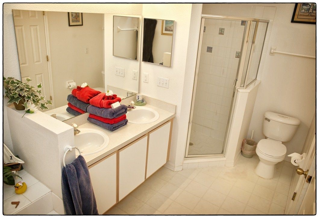 Une salle de bain avec deux lavabos, un miroir, une douche et des toilettes.