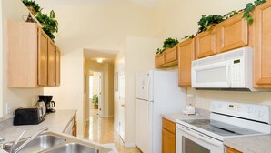 Une cuisine avec des meubles de rangement en bois, un réfrigérateur blanc, une cuisinière et un four à micro-ondes.