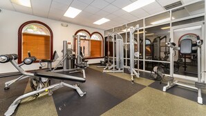 Une salle de sport équipée de divers appareils d’exercice, notamment des machines de musculation et un banc.