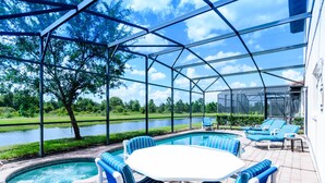 Un espace extérieur abrité comprenant une piscine, des chaises longues et une vue sur un lac et la verdure environnante.
