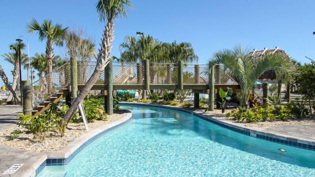 A clear swimming pool with a wooden bridge and palm trees. - Ov3851 - Champions Gate Resort - 4 Bed 3 Baths Townhome (Davenport)