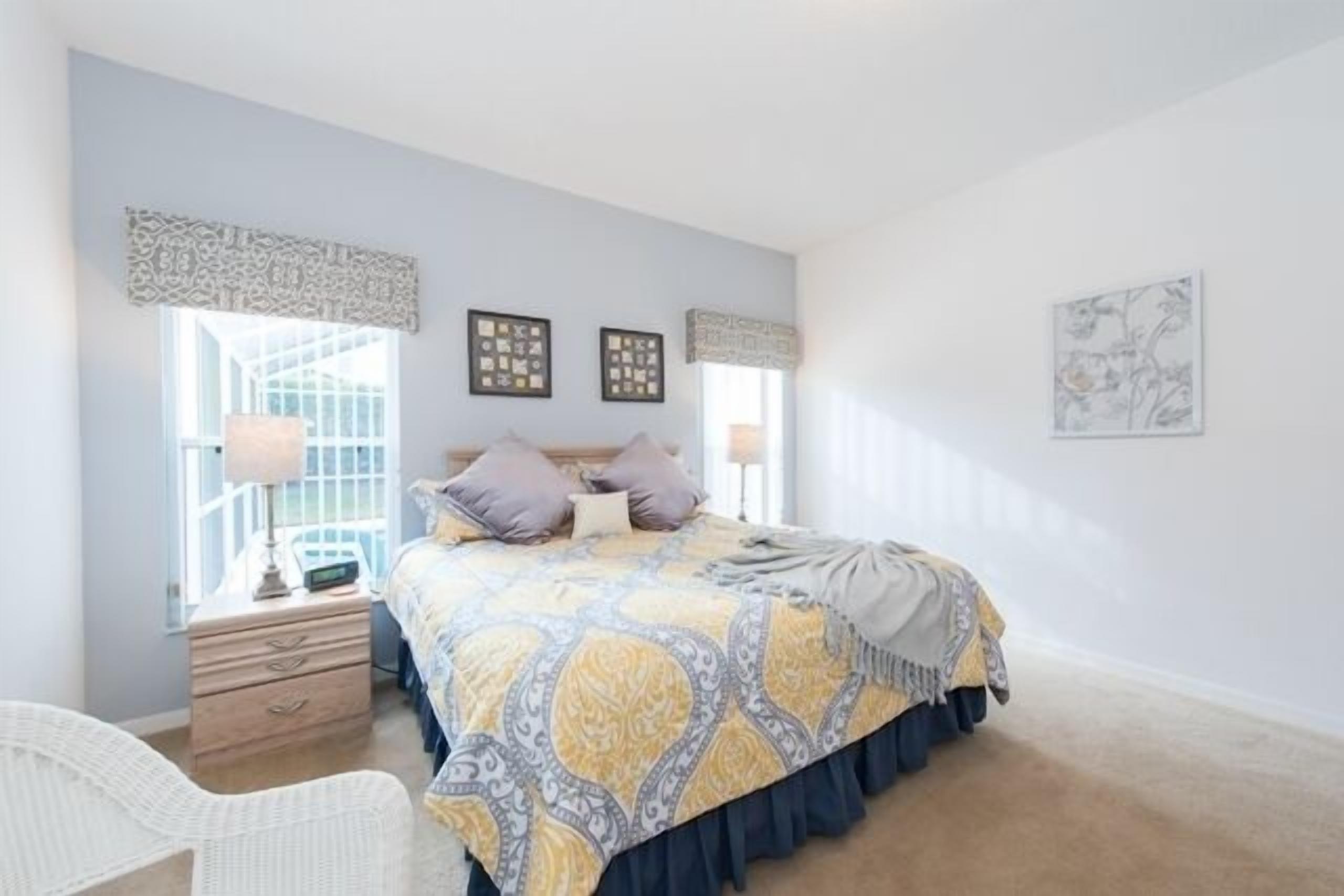 A bedroom with a bed, bedside tables, a chair, and artwork on the walls.