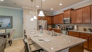 A modern kitchen with granite countertops, stainless steel appliances, and wooden cabinets. - Ov4105 - Windsor At Westside - 4 Bed 3.5 Baths Townhome (Kissimmee)