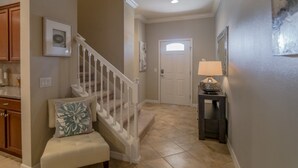 A hallway with a staircase, a door, a bench, and a lamp. - Ov4105 - Windsor At Westside - 4 Bed 3.5 Baths Townhome (Kissimmee)