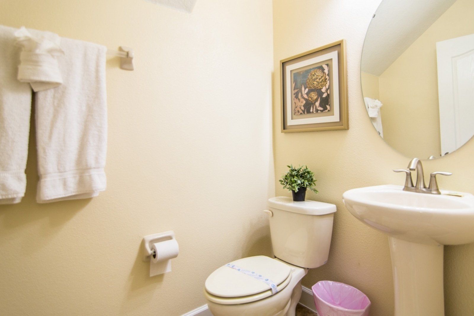 A bathroom with a toilet, sink, and a framed picture on the wall.