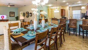 A dining area with a long table set for six, surrounded by wicker chairs. - Ov4089 - Champions Gate Resort - 5 Bed 4.5 Baths Villa (Davenport)