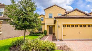 A two-story house with a garage, a well-maintained lawn, and a tree in the front yard. - Ov4089 - Champions Gate Resort - 5 Bed 4.5 Baths Villa (Davenport)