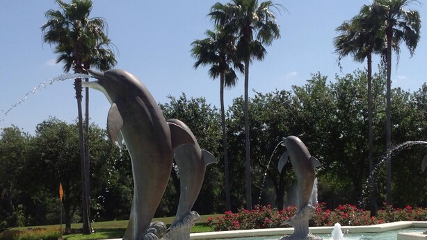 A fountain with dolphin sculptures in a landscaped area with palm trees and flowers. - Ov2568 - Emerald Island - 3 Bed 2.5 Baths Townhome (Kissimmee)