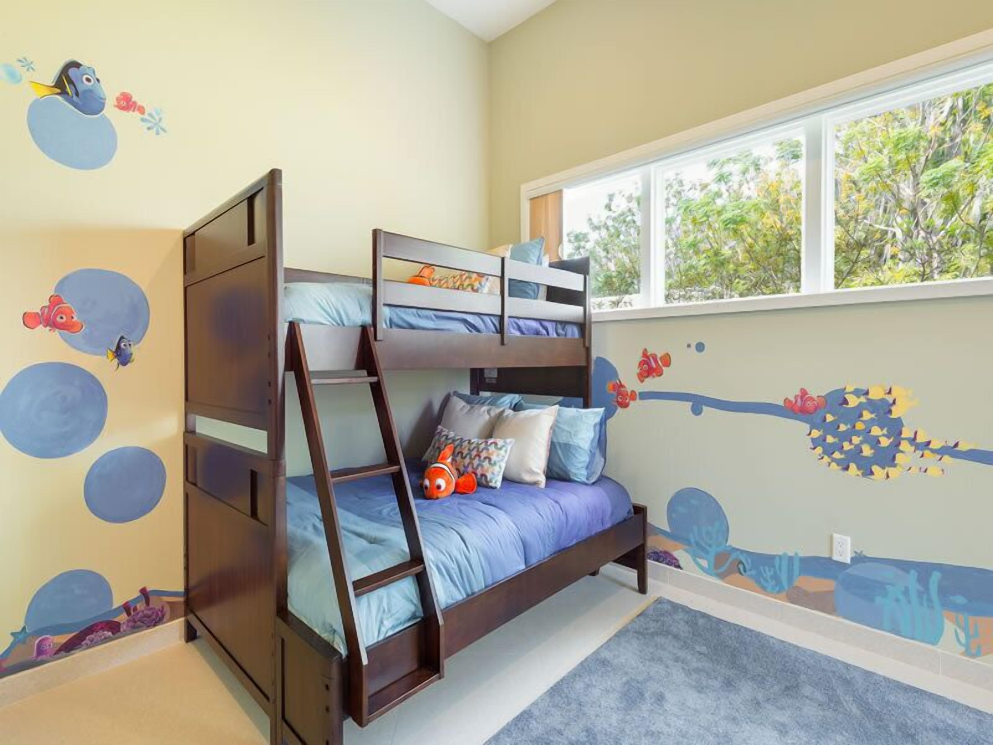 A bunk bed room with a window, a ladder, and wall decorations.